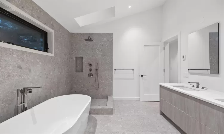 Bathroom featuring vaulted ceiling with skylight, vanity, and plus walk in shower