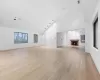 Unfurnished living room featuring light wood-type flooring and high vaulted ceiling