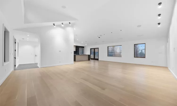 Unfurnished living room featuring light hardwood / wood-style floors and high vaulted ceiling