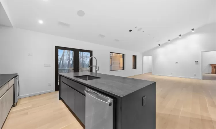 Kitchen with dishwasher, an island with sink, light hardwood / wood-style floors, and sink