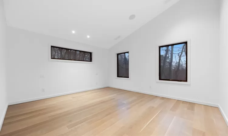 Spare room with light wood-type flooring and lofted ceiling