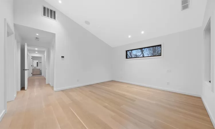 Unfurnished room featuring light wood-type flooring and high vaulted ceiling