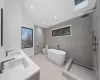 Full bathroom with vanity, lofted ceiling with skylight, separate shower and tub, tile walls, and toilet