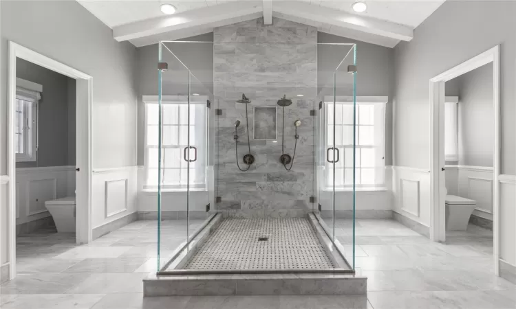 Bathroom featuring a wealth of natural light, lofted ceiling with beams, and toilet