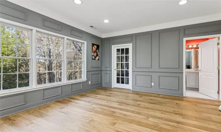 Empty room featuring crown molding, plenty of natural light, and light wood-type flooring