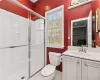 Bathroom featuring tile patterned floors, a shower with door, vanity, and toilet