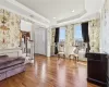 Living area with hardwood / wood-style floors, a raised ceiling, and ornamental molding