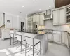 Kitchen with stainless steel appliances, wall chimney range hood, cream cabinets, a kitchen bar, and a kitchen island