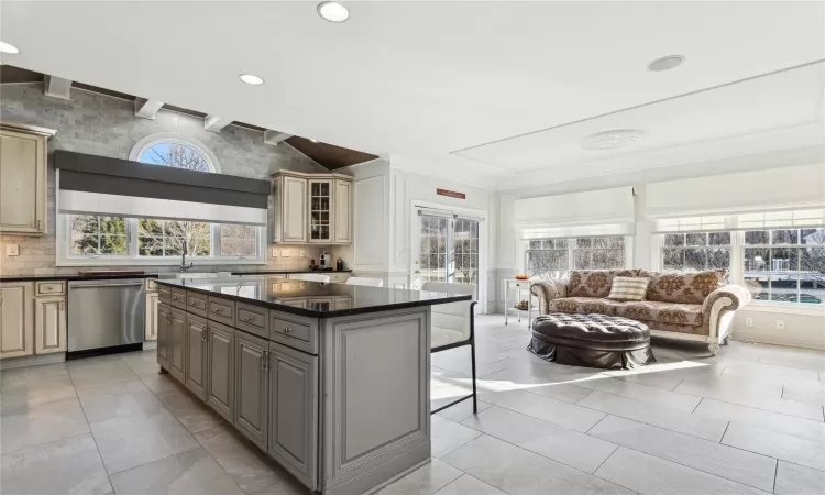 Kitchen featuring a wealth of natural light, a center island, a kitchen breakfast bar, stainless steel dishwasher, and gray cabinets