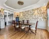 Dining area featuring hardwood / wood-style floors, decorative columns, a raised ceiling, and ornamental molding