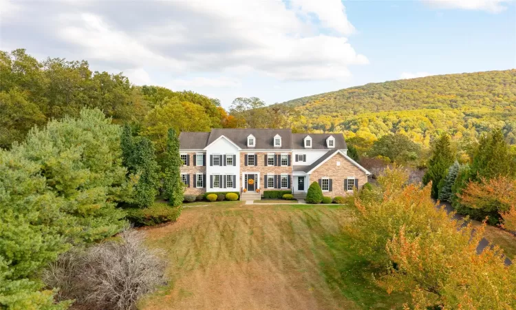 View of front of home with a mountain view and a front lawn