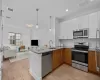 Kitchen with sink, appliances with stainless steel finishes, tasteful backsplash, decorative light fixtures, and white cabinetry