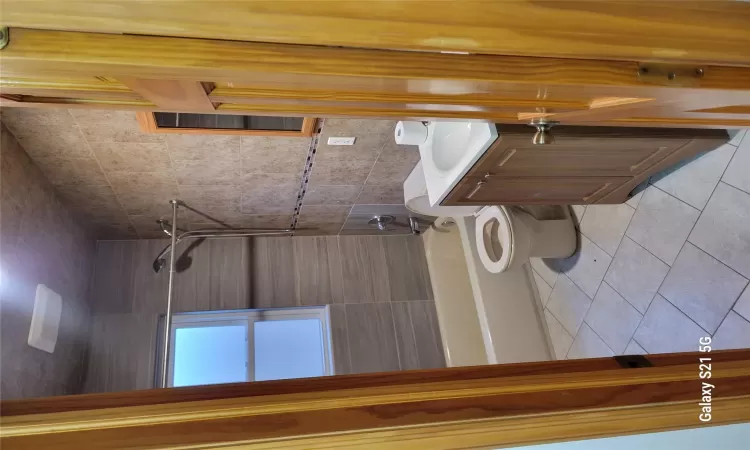 Full bathroom featuring vanity, tiled shower / bath, tile patterned flooring, toilet, and tile walls