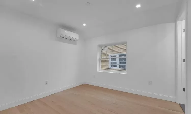 Spare room with a wall mounted AC and light hardwood / wood-style floors