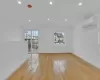 Empty room with a wall mounted AC, lofted ceiling, and light wood-type flooring