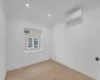 Unfurnished room featuring a wall mounted air conditioner and light hardwood / wood-style flooring