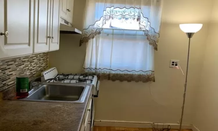 Kitchen featuring white cabinets, decorative backsplash, and sink