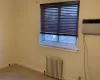 Carpeted spare room featuring a wall mounted AC, plenty of natural light, and radiator