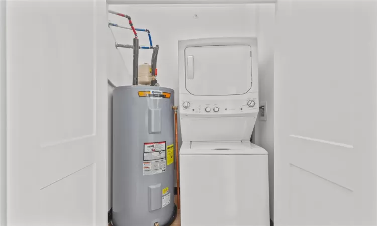 Laundry room featuring stacked washer and clothes dryer and water heater