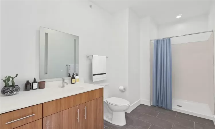 Bathroom with toilet, vanity, tile patterned floors, and curtained shower