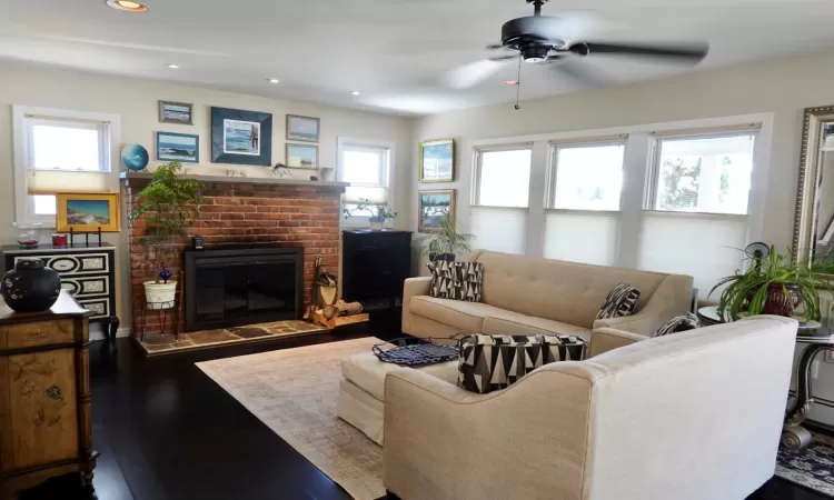 Living room with a fireplace, hardwood / wood-style floors, a wealth of natural light, and ceiling fan