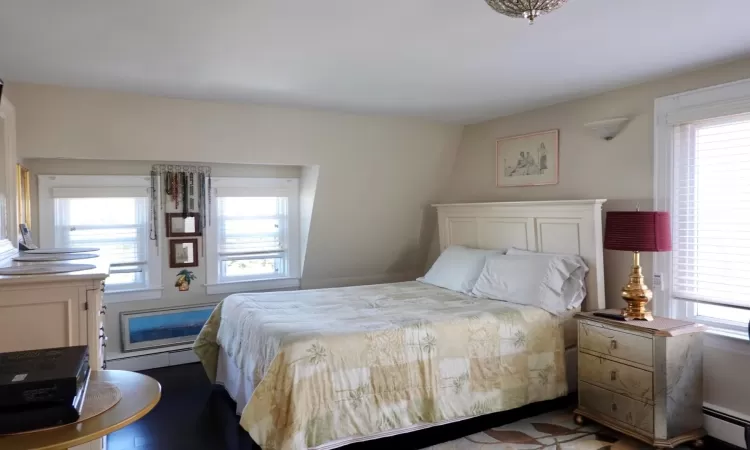 Bedroom featuring wood-type flooring and a baseboard heating unit