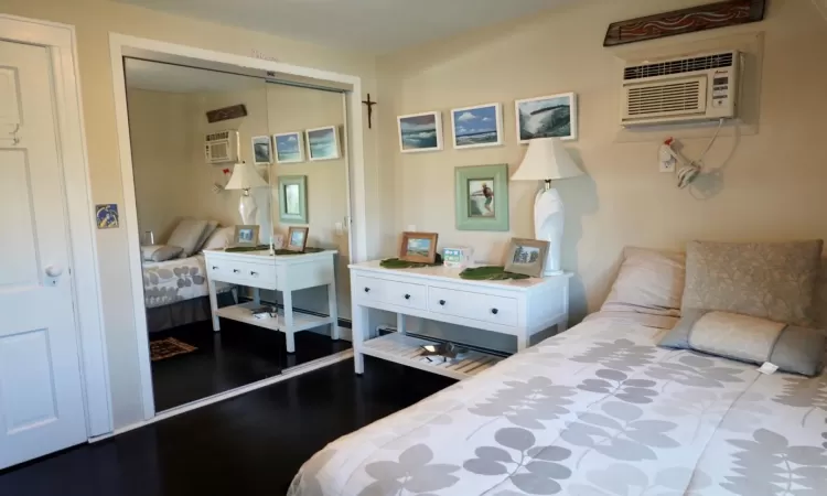 Bedroom featuring a wall mounted air conditioner, wood-type flooring, and a closet