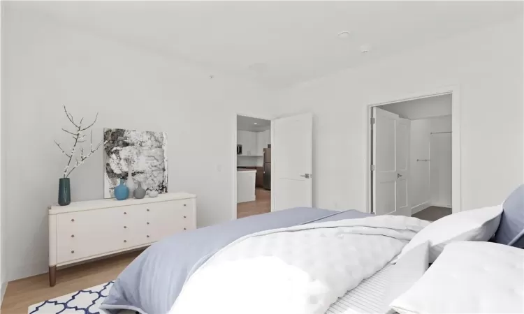 Bedroom with hardwood / wood-style flooring, stainless steel fridge, and connected bathroom