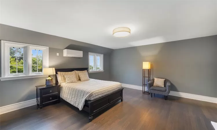 Bedroom featuring an AC wall unit, lofted ceiling, and dark hardwood / wood-style floors