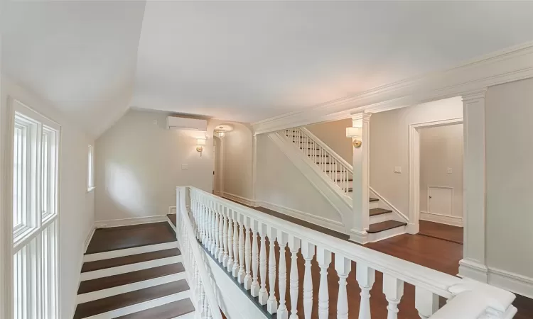 Stairway featuring hardwood / wood-style flooring, an AC wall unit, and vaulted ceiling