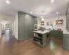 Kitchen with decorative backsplash, green cabinets, hanging light fixtures, and dark wood-type flooring