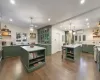 Kitchen featuring decorative backsplash, stainless steel appliances, a wall unit AC, green cabinetry, and a center island