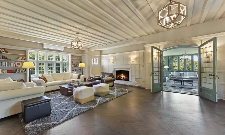 Living room with dark parquet flooring, an AC wall unit, and french doors