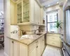 Kitchen featuring cream cabinetry, light stone counters, light tile patterned floors, and sink