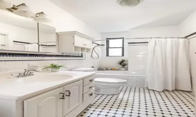 Full bathroom with toilet, vanity, tasteful backsplash, and shower / tub combo with curtain