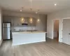 Kitchen featuring appliances with stainless steel finishes, gray cabinets, a center island with sink, and sink