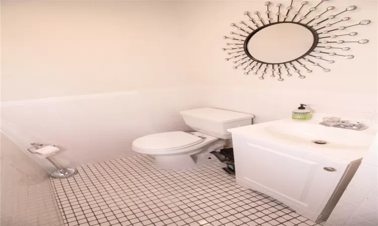 Bathroom with tile patterned floors, vanity, tile walls, and toilet