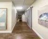 Hallway featuring a drop ceiling, a barn door, and dark hardwood / wood-style flooring