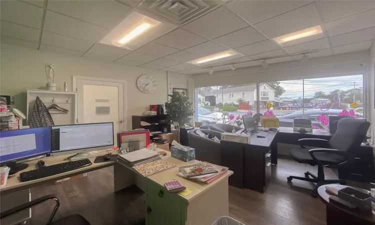 Home office with a drop ceiling and dark wood-type flooring