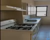 Kitchen with ventilation hood, sink, light tile patterned floors, and white gas range oven