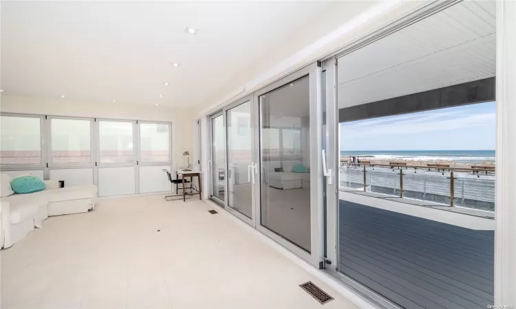 Sunroom / solarium featuring a beach view and a water view