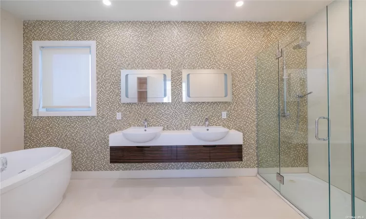 Bathroom featuring vanity, tile walls, plus walk in shower, and tasteful backsplash