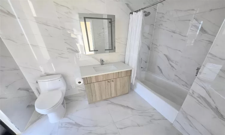 Full bathroom featuring vanity, shower / bathtub combination with curtain, and toilet