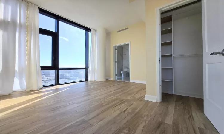 Unfurnished bedroom with hardwood / wood-style flooring and expansive windows