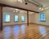 Empty room with beamed ceiling and light hardwood / wood-style flooring