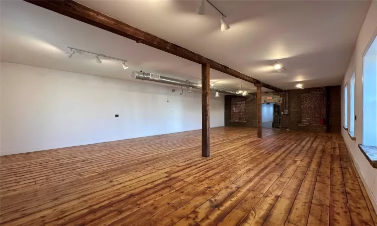 Basement featuring wood-type flooring and brick wall