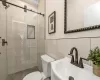 Bathroom with walk in shower, toilet, tile walls, and sink