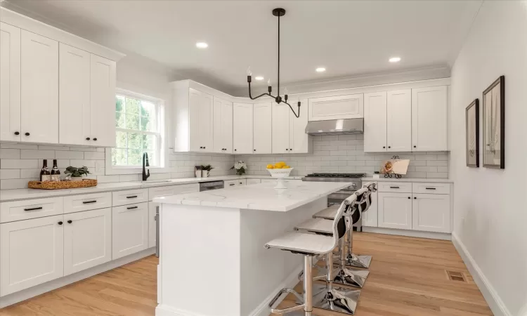 Kitchen featuring white cabinetry, a kitchen island, and light oak wood flooring