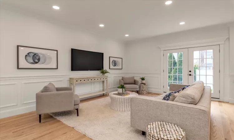 Den with french doors, ornamental molding, and light oak wood flooring