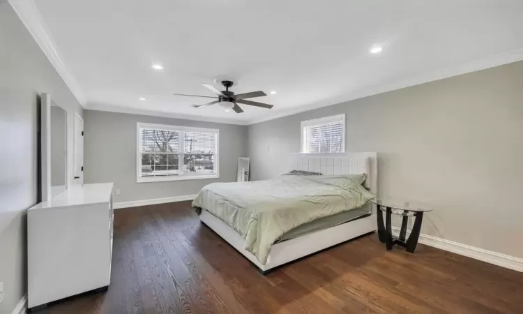 Bedroom with ceiling fan, dark wood-type flooring, and ornamental molding